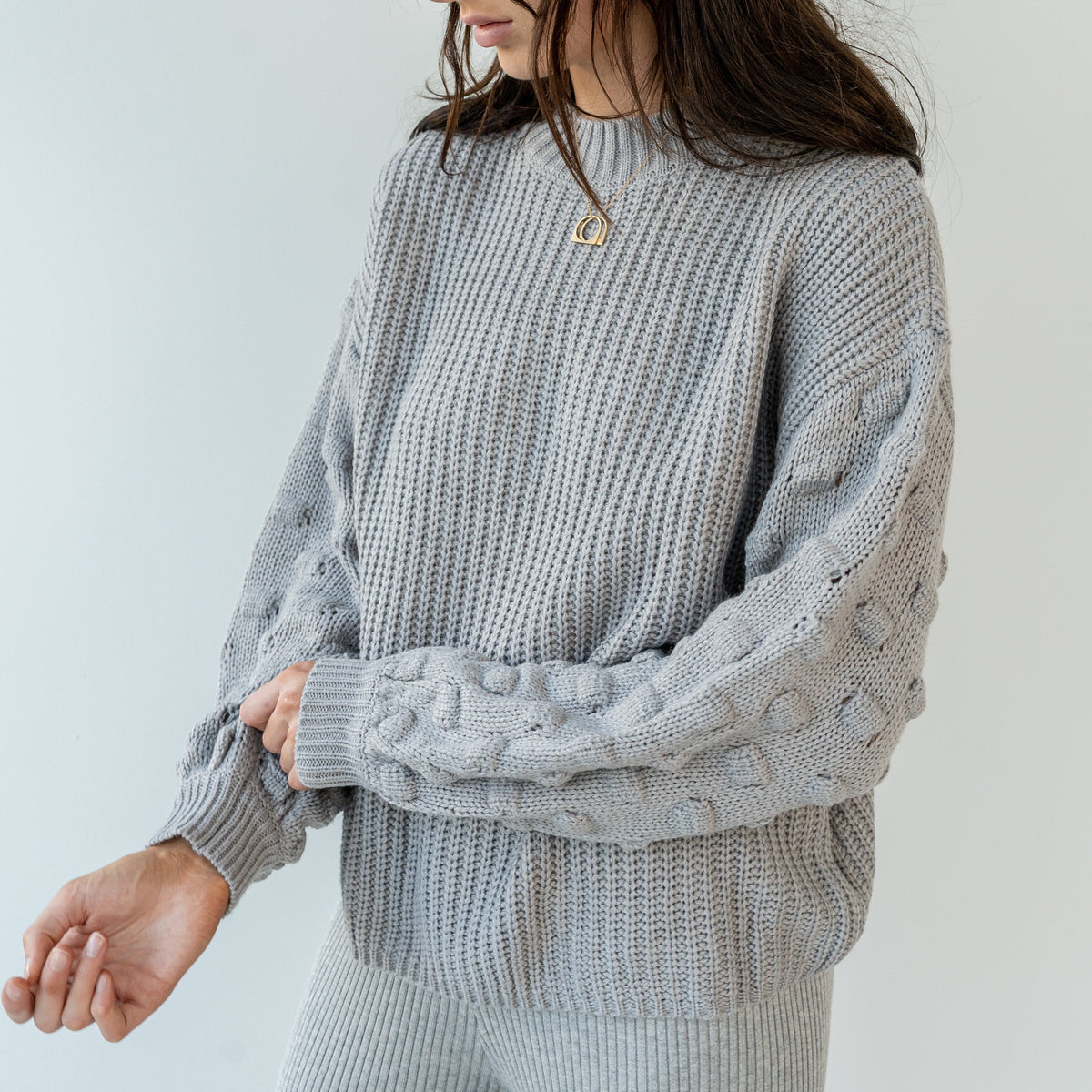 OKAKIE grey popcorn sleeve knit sweater with a ribbed crew neck and relaxed drop shoulders on a model