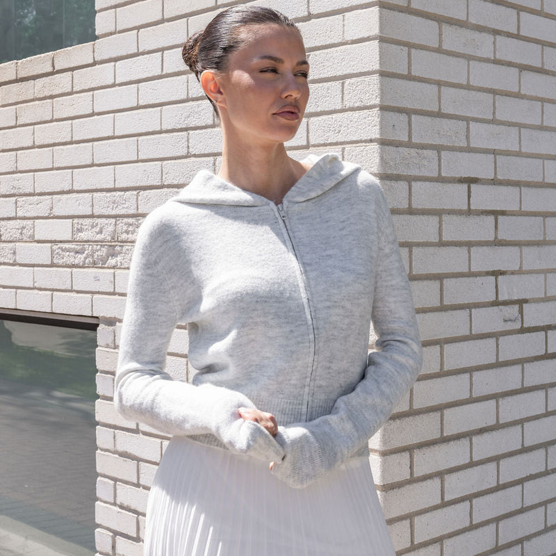 OKAKIE heather grey cotton knit zip hoodie with a relaxed fit, hood, and long sleeves worn by a woman outdoors.