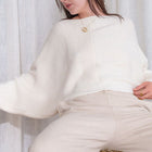 OKAKIE ivory knit sweater with a relaxed fit, wide statement sleeves, and a round neckline worn by a model.