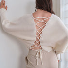 OKAKIE ivory knit sweater featuring a dramatic lace-up back design, wide sleeves, and a relaxed, textured fit.