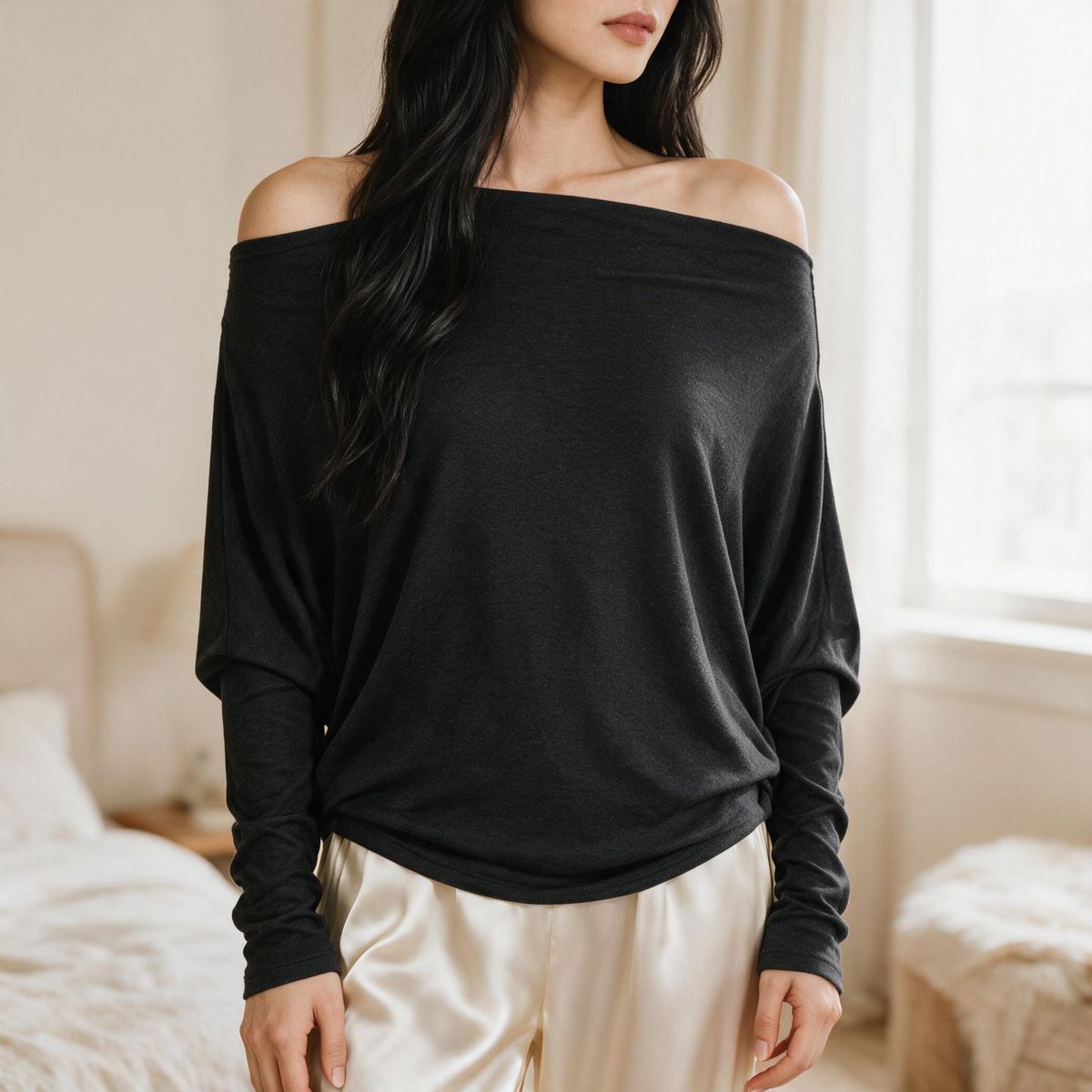 OKAKIE Maëlle black hacci knit top with a wide boat neckline and relaxed dolman sleeves worn off the shoulder