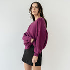 Model wearing OKAKIE magenta heavy tunic knit sweater with drop shoulders and textured knit, paired with black skirt