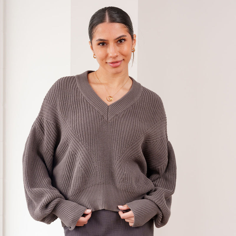 OKAKIE The Marais cotton-blend sweater in dark grey with a deep V-neck, drop shoulders, and textured knit detail.