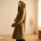 Model wearing an OKAKIE olive heavyweight hooded cardigan with an open front, longline silhouette, and patch pockets.