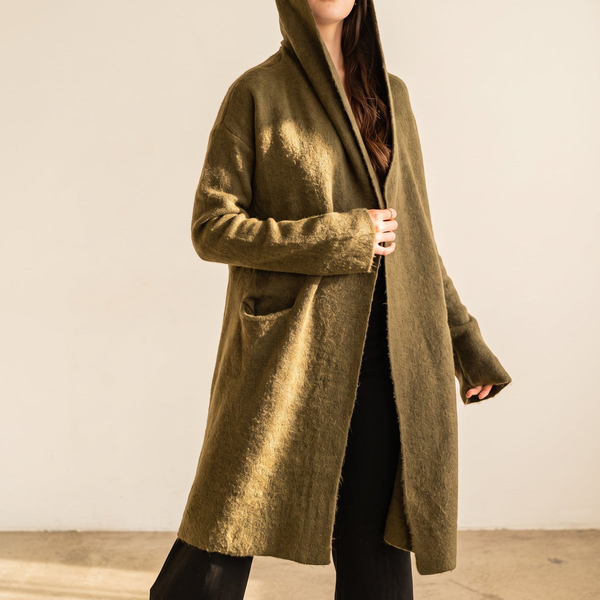 OKAKIE Adrienne heavyweight olive green hooded cardigan with an open front, longline silhouette, and patch pockets.