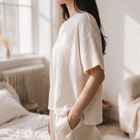 OKAKIE oversized cream raw cotton tee with textured slub finish and dropped shoulders worn by a woman in a bedroom