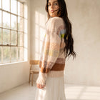 OKAKIE model wearing a plush, heavy-weight pastel striped sweater with drop shoulders in a sunlit studio.