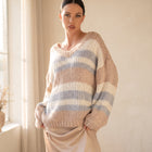 OKAKIE oversized pastel striped V-neck knitted sweater tunic worn by a woman in a sunlit room