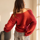 OKAKIE red cable knit sweater with off-shoulder neckline and wide dolman sleeves worn by a woman.