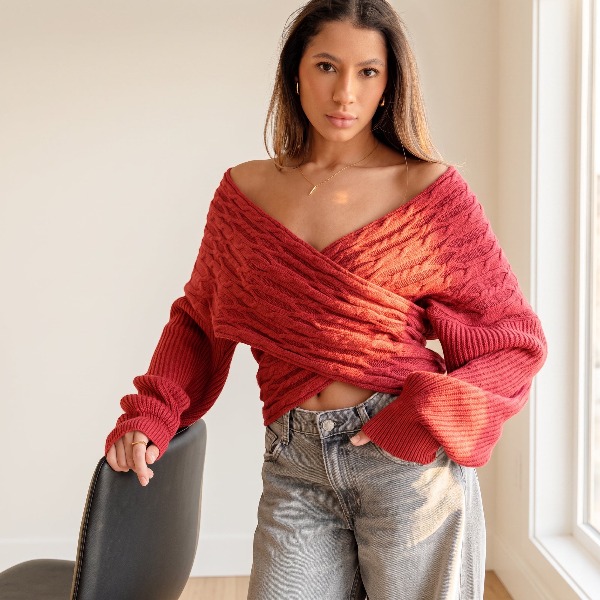 Model wearing an OKAKIE red cable knit sweater with a criss-cross V-neckline and wide dolman sleeves