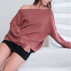 OKAKIE oversized ribbed knit tunic sweater in a soft mauve tone with dropped shoulders and a wide off-shoulder neck.