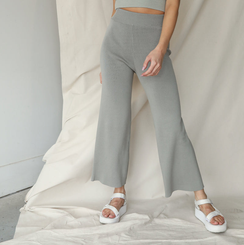 OKAKIE sage green soft knit wide-leg pants with a high-rise ribbed waistband and fluid drape on a model