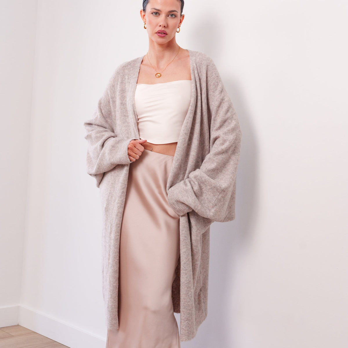 Model wearing an OKAKIE beige soft modal drape cardigan with a relaxed maxi silhouette and voluminous sleeves.