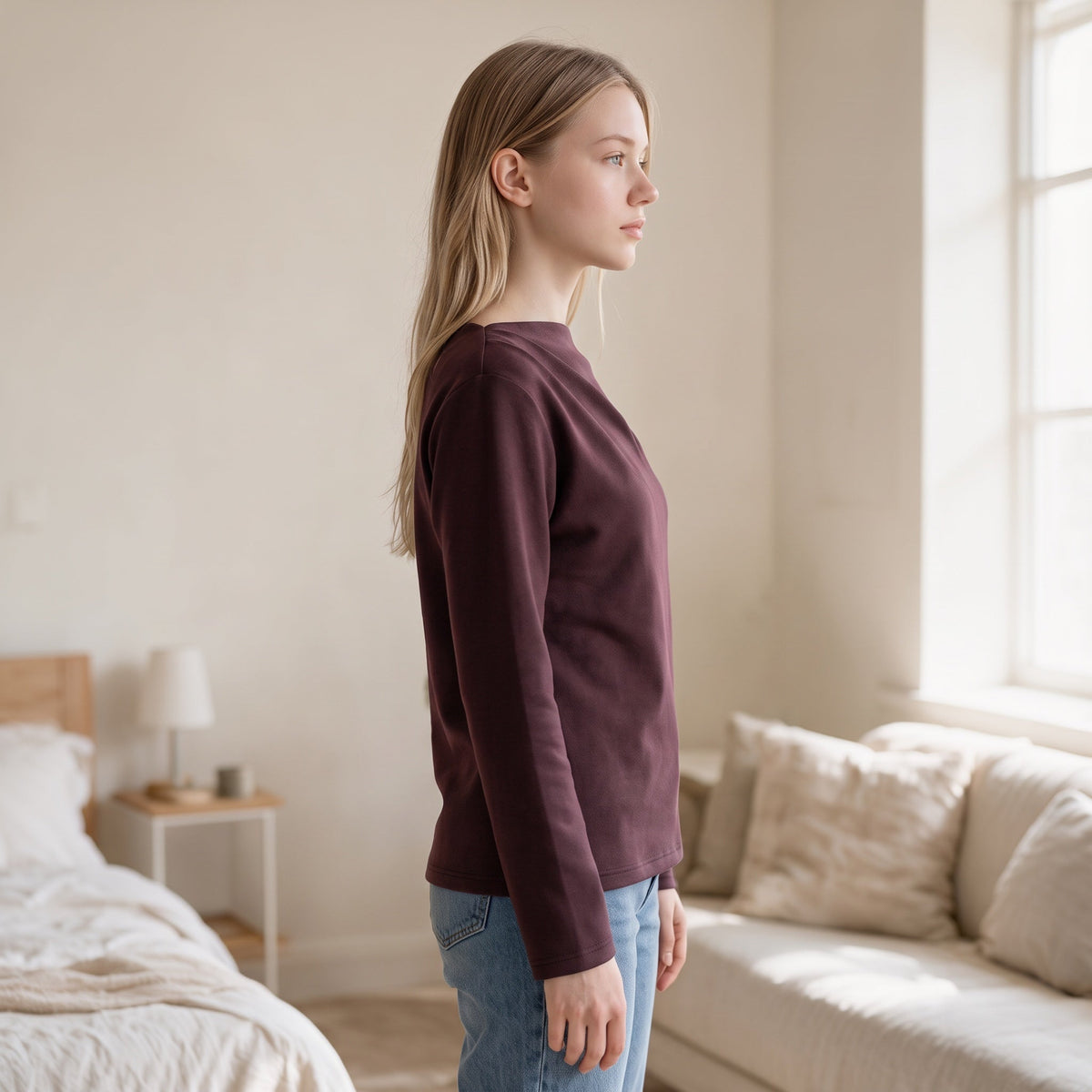 OKAKIE Solène asymmetric scuba knit top in deep plum, featuring a long-sleeve, slim-fit design on a blonde model.