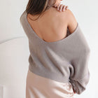 OKAKIE taupe reversible sweater with a dramatic low-back neckline and relaxed oversized fit worn off-the-shoulder