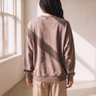 Back view of a woman wearing an OKAKIE oversized vintage wash fleece pullover with balloon sleeves in a neutral tone.