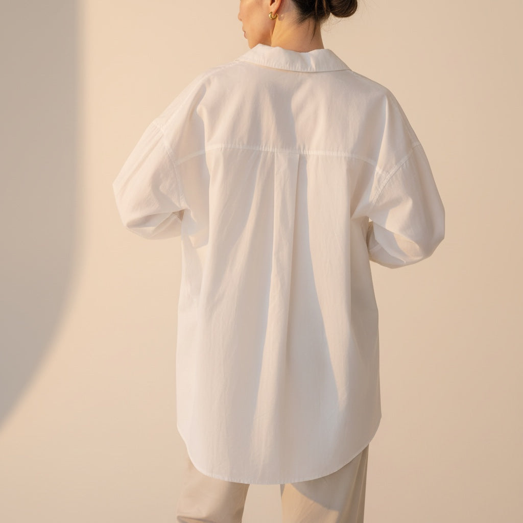 Back view of OKAKIE white cotton poplin boyfriend over-shirt with a loose fit and high-low hem on a model