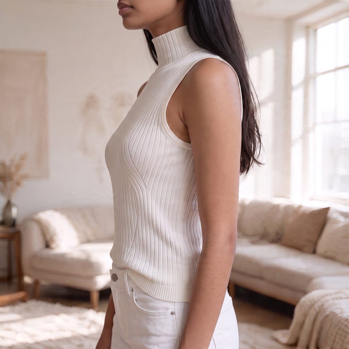 OKAKIE white sleeveless high neck rib knit top with curved detailing worn by a model in a bright living room